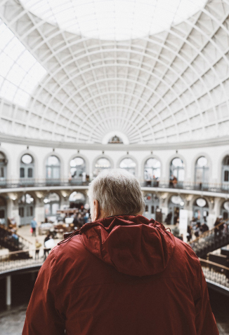 Older man wearing red jacket inside museum